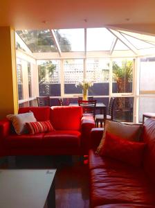 una sala de estar con sofás rojos y una gran ventana. en Waterloo Cottage, en Hobart