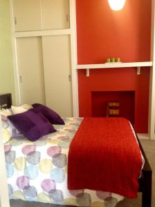 1 dormitorio con 1 cama con pared roja en Waterloo Cottage, en Hobart