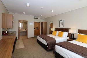 Habitación de hotel con 2 camas y baño en The Victoria Hotel Dunedin en Dunedin