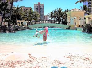 a person standing in the water with a surfboard at The Towers of Chevron Renaissance - Holidays Gold Coast in Gold Coast