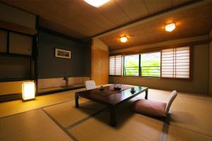 ein Wohnzimmer mit einem Tisch, Stühlen und einem Fenster in der Unterkunft Nansuikaku in Miyawaka