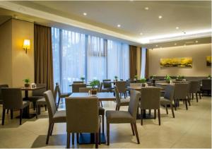 a restaurant with tables and chairs and a large window at Home Inn Plus Qingdao Yinchuan West Road Software Park in Qingdao