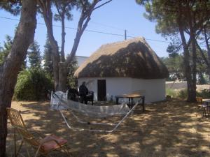 a hut with a thatched roof with chairs and a table at Finca Malyma with 2 villas and 1 apartment, beach front 10,000m2 botanic garden in Zahora