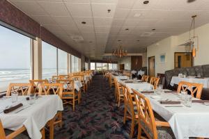 een eetkamer met witte tafels en houten stoelen bij Shilo Inn Suites Newport in Newport