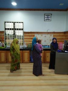 Un groupe de femmes debout dans une cuisine dans l'établissement HOMESTAY Kb Wakaf Kayu, à Kota Bharu