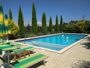 a swimming pool with green lounge chairs and trees at Holiday Home Villa Bobolino in Montelupo Fiorentino