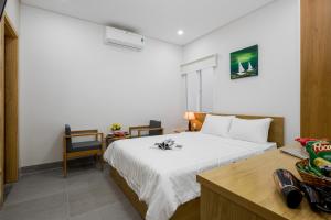 - une chambre avec un lit blanc et un bureau avec une chaise dans l'établissement Anh Villa Hotel, à Đà Nẵng