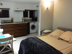 a bedroom with a bed and a kitchen with a washing machine at Villa Cathy T2 in Aix-les-Bains