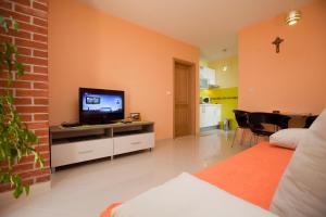 a living room with a tv on a cabinet with a bed at Villa Marija Podgora in Podgora