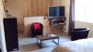 Habitación con cama, mesa y TV. en La Petite Forge, en Oye-et-Pallet