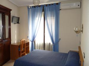 sypialnia z niebieskim łóżkiem i oknem w obiekcie Hostal Fernandez w Madrycie