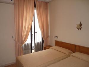 sypialnia z 2 łóżkami i oknem z zasłonami w obiekcie Hostal Fernandez w Madrycie