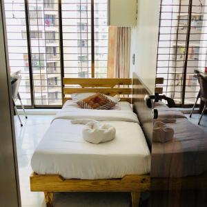 two beds with towels on them in a room with windows at Pinaki Comfort Stay in Mumbai