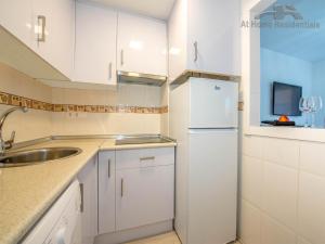 トレビエハにあるAt home Residentialsの白いキャビネット、シンク、冷蔵庫付きのキッチンが備わります。