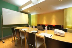 Chisun Inn Nagoya في ناغويا: قاعة اجتماعات مع طاولة وكراسي وشاشة عرض