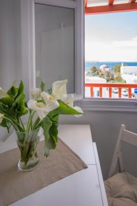 un jarrón de flores sobre una mesa con una ventana en Arodou Studio and Apartment, en Mykonos ciudad