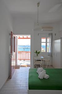 a bedroom with a green bed with a view of the ocean at Arodou Studio and Apartment in Mikonos