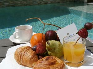 um prato de frutas e croissants e um copo de sumo de laranja em Tulip inn Sainte Clotilde em Saint-Denis