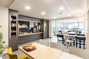 a dining room with tables and chairs and a cafeteria at B&B HOTEL La Queue En Brie in La Queue-en-Brie