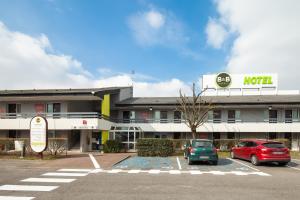 een hotel met twee auto's geparkeerd op een parkeerplaats bij B&B HOTEL La Queue En Brie in La Queue-en-Brie