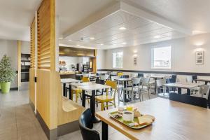 a dining room with tables and yellow chairs at B&B HOTEL Lyon Grand Stade Meyzieu in Meyzieu