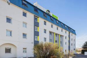 an apartment building with a sign on top at B&B HOTEL Lyon Grand Stade Meyzieu in Meyzieu