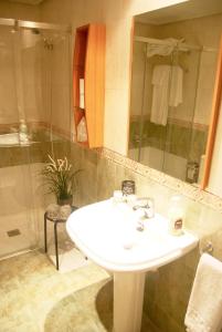 een badkamer met een witte wastafel en een douche bij Apartamentos Turisticos ARCH in León