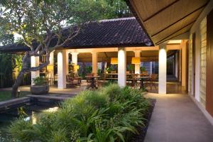 an outdoor patio with tables and chairs and a pond at Atelier TE Designer Guesthouse in Sanur