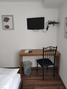 a bedroom with a desk with a television and a chair at Gasthaus Zum Ochsen in Hochstadt