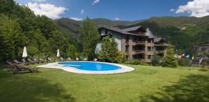 a large yard with a swimming pool in front of a building at Abba Xalet Suites Hotel in Sispony