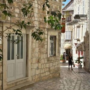 a woman walking down a street next to a stone building at Hvar apartment 4 in Hvar