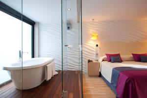 a bathroom with a tub and a bed and a bath tub at Vincci Selección Posada del Patio in Málaga