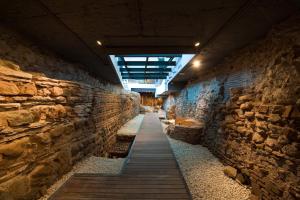 a stone wall with a wooden walkway in a building at Vincci Selección Posada del Patio in Málaga