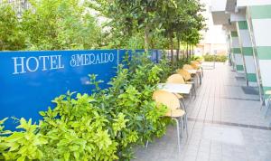 una fila de mesas y sillas junto a una pared azul en Hotel Smeraldo, en Tortoreto Lido