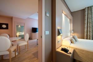 a hotel room with a bed and a dining room at Vincci Selección Posada del Patio in Málaga