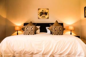 a bedroom with a large white bed with two lamps at Gerald's Gift Guest House in Addo