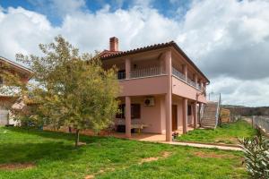 une maison rose avec un balcon et un arbre dans l'établissement Apartments Ines, à Pula