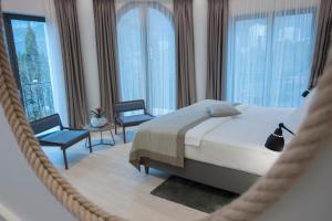 a bedroom with a bed and two chairs and windows at Hotel Majestic in Budva