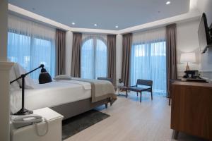 a bedroom with a bed and a desk and windows at Hotel Majestic in Budva