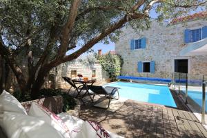 a pool with a table and chairs next to a house at Olive's Hug in Poljana