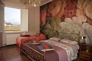 ルッカにあるLiberi Mercanti - guest house affittacamereのベッドルーム1室(ベッド2台付)が備わります。壁には絵画が飾られています。