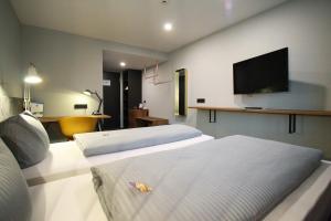a hotel room with two beds and a flat screen tv at Novitel Hotel Kirchheim - München Messe in Kirchheim