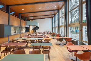 uma cafetaria com mesas, cadeiras e janelas em Bern Youth Hostel em Berna