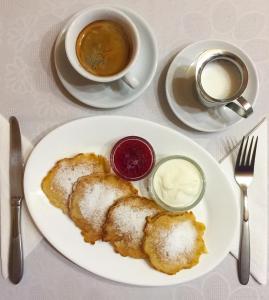 a plate of food with powdered sugar and a cup of coffee at Villa Iris in Yaremche