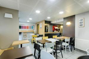 une salle à manger avec des tables et des chaises dans un restaurant dans l'établissement B&B HOTEL Rouen Parc des Expos Zénith, à Le Grand-Quevilly