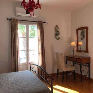 a bedroom with a bed and a desk and a window at Oklacà Patmos Beach Rooms in Patmos