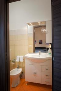 a bathroom with a sink and a toilet and a mirror at Asaro Camere in Campobello di Licata