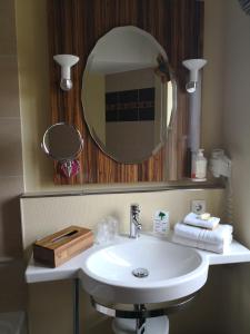 ein Badezimmer mit einem weißen Waschbecken und einem Spiegel in der Unterkunft Hotel Sonnenhof in Perl