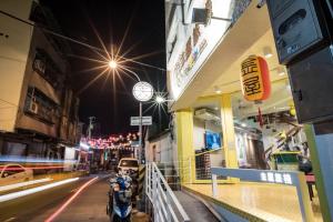 King Wow Inn في تاى نان: شارع في الليل به دراجة نارية متوقفة أمام متجر