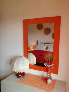 Schlafzimmer mit einem roten Bett und einem Spiegel in der Unterkunft Appartamento Gennirco in Baunei